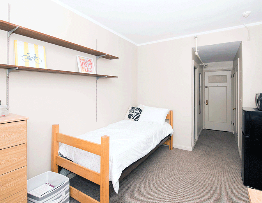 A bedroom with a single bed , dresser , and shelves.