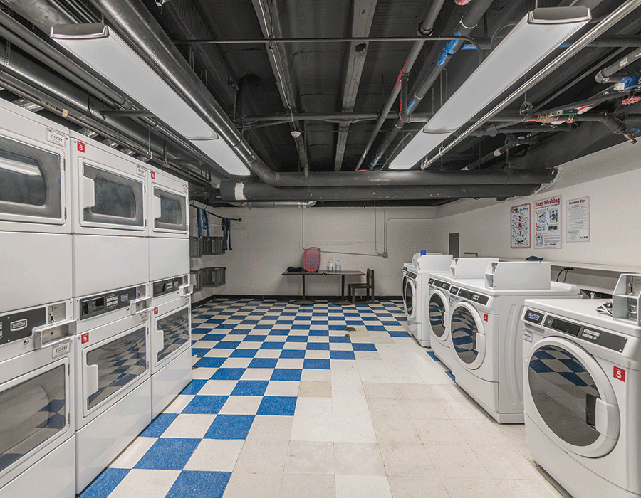 A laundromat with a blue and white checkered floor and lots of washers and dryers.