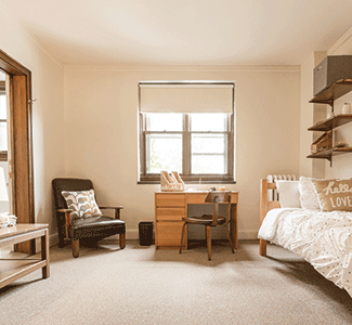 A bedroom with a bed , desk , chair and coffee table.