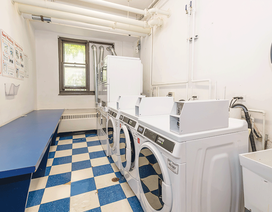 A laundry room with a blue and white checkered floor and a row of washers and dryers.