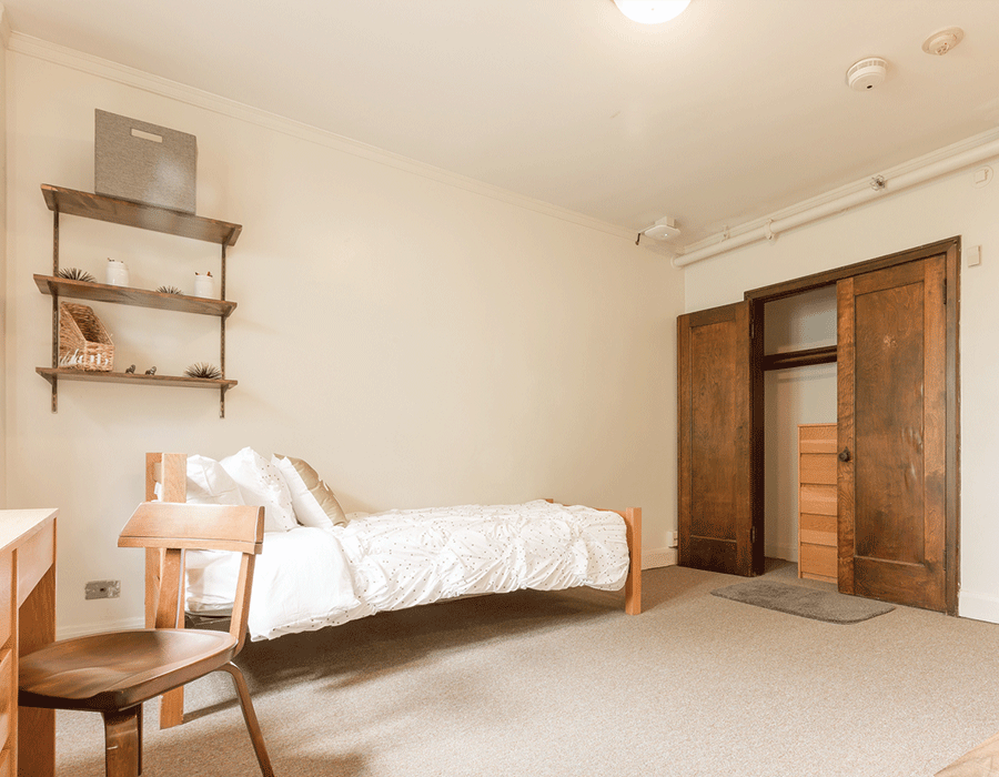 A bedroom with a bed , chair , desk and closet.