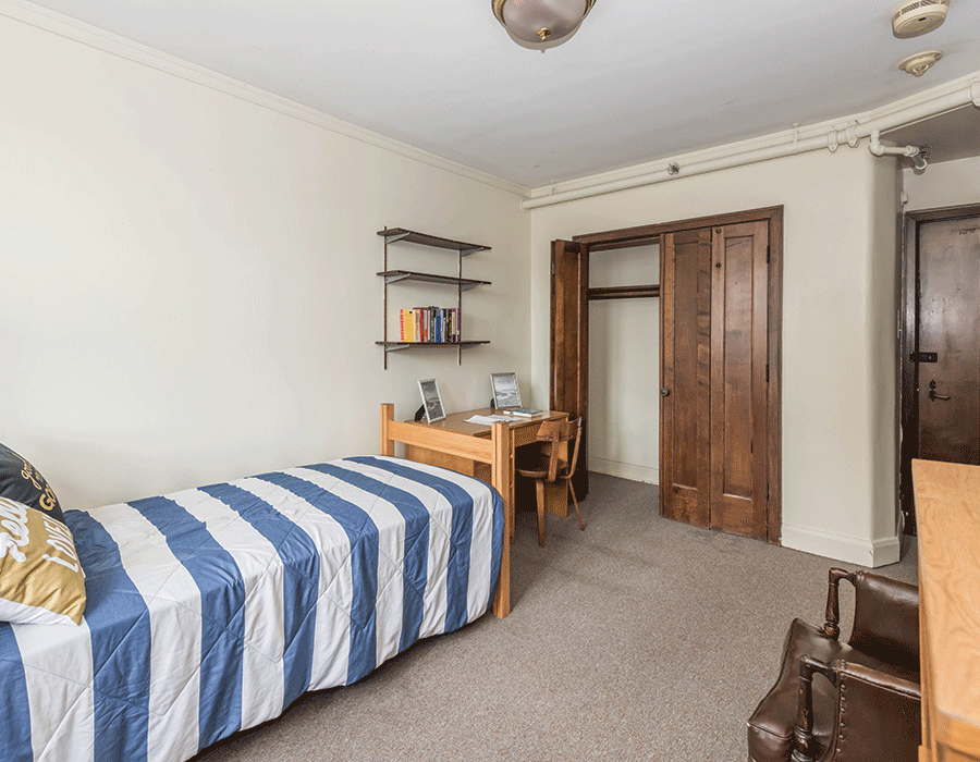 A bedroom with a single bed , desk , chair and closet.