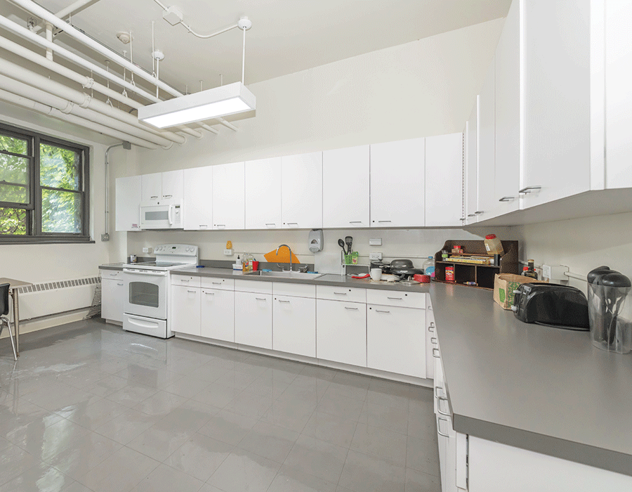 A kitchen with white cabinets , a stove , a microwave , and a sink.