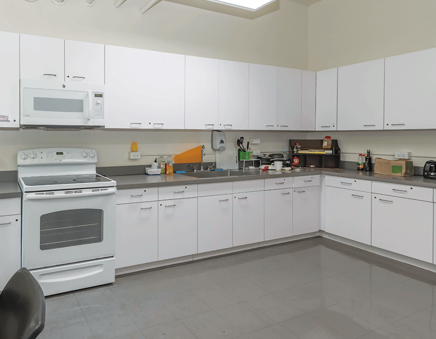 A kitchen with white cabinets and a stove and microwave