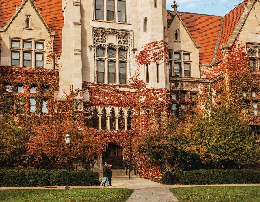 A couple of people are walking in front of a large building.