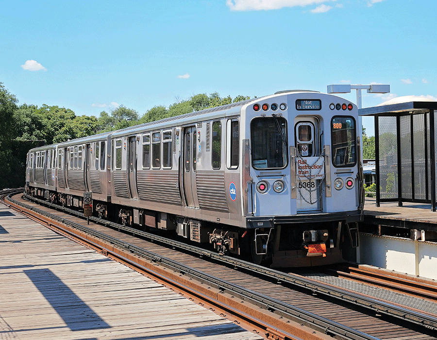 A subway train is pulling into a station on a sunny day.