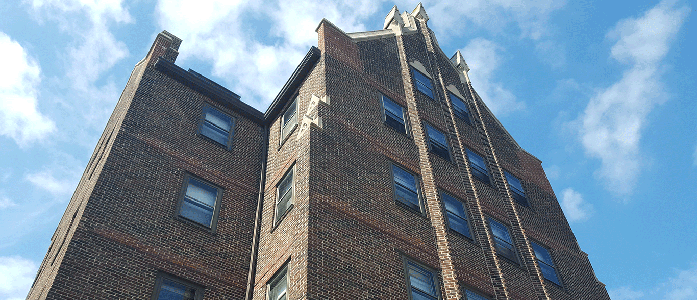 Looking up at a tall brick building with a blue sky in the background