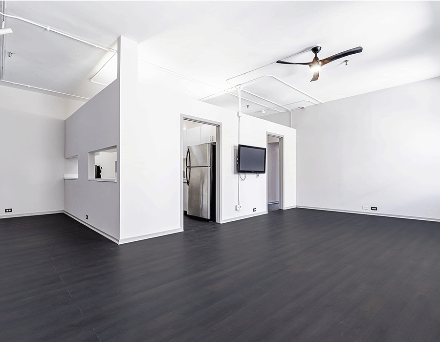 A large empty room with a ceiling fan and a flat screen tv on the wall.