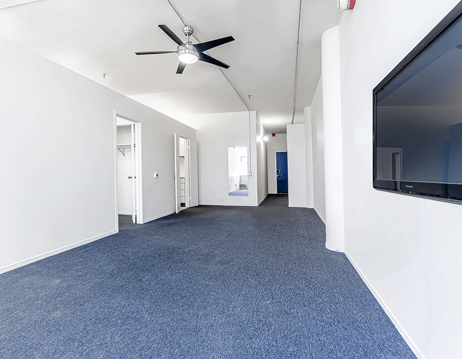 An empty room with a ceiling fan and a flat screen tv