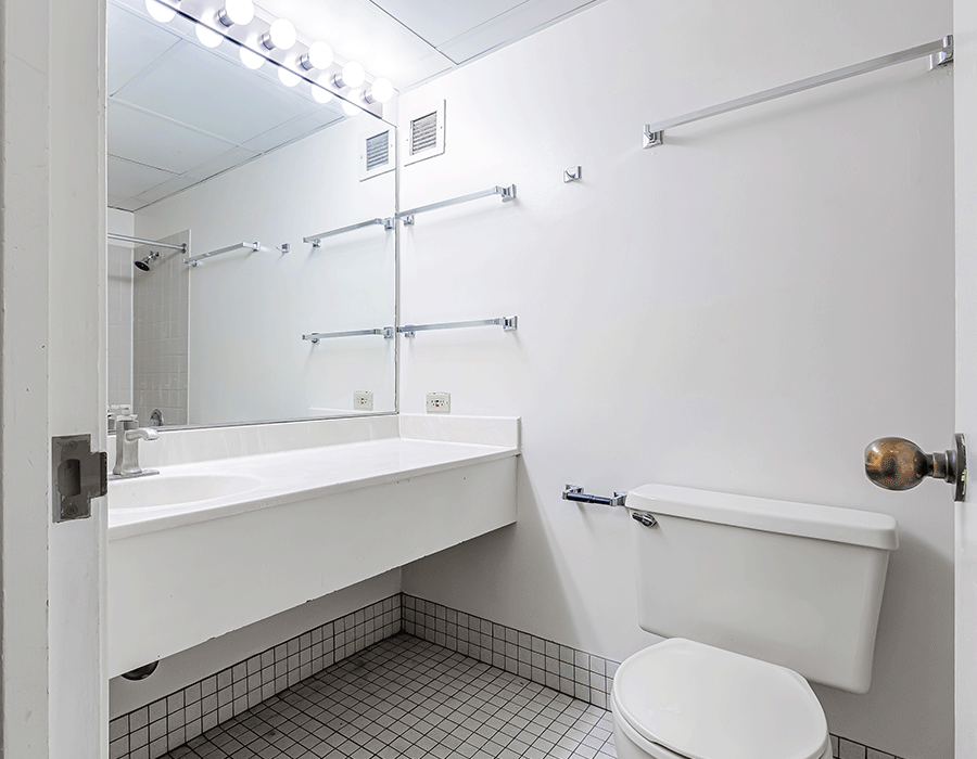A bathroom with a toilet , sink and mirror.