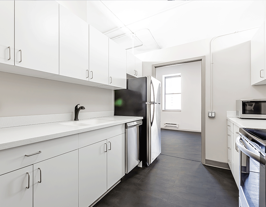A kitchen with white cabinets and a black refrigerator
