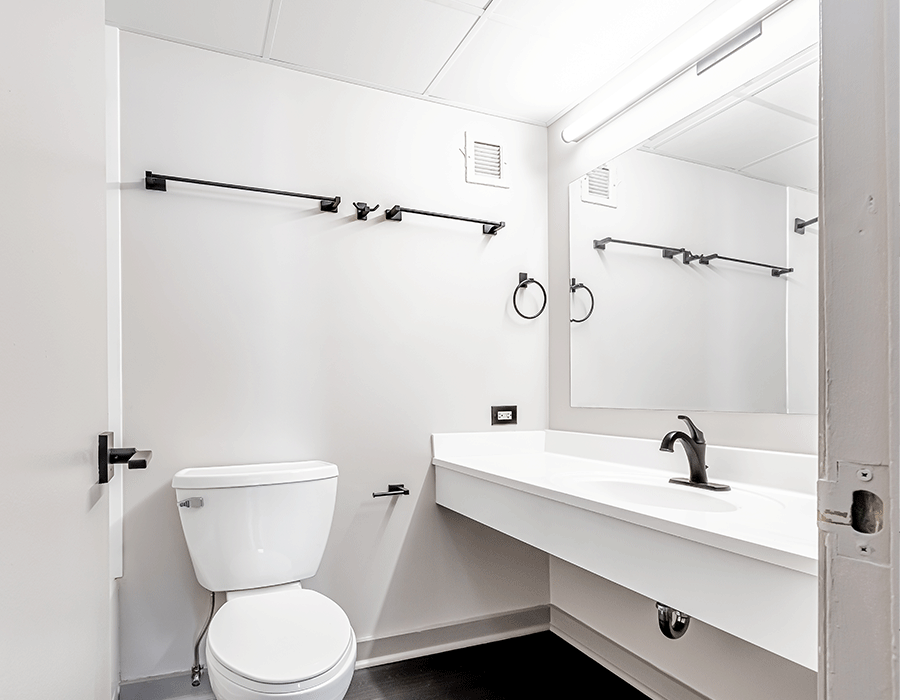 A bathroom with a toilet , sink and mirror.