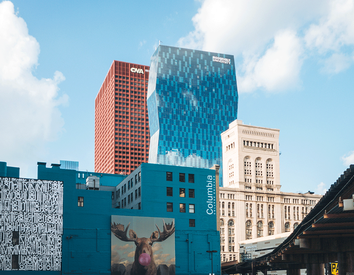 A moose is painted on the side of a building in a city.