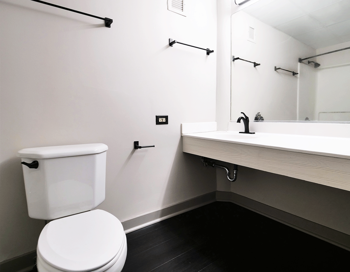A bathroom with a toilet , sink and mirror.
