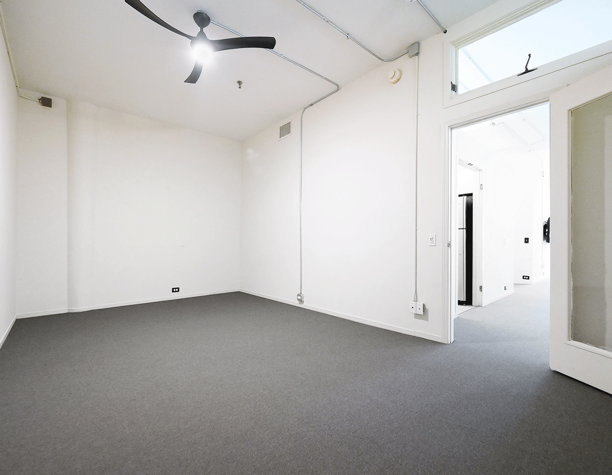 An empty room with white walls and a ceiling fan