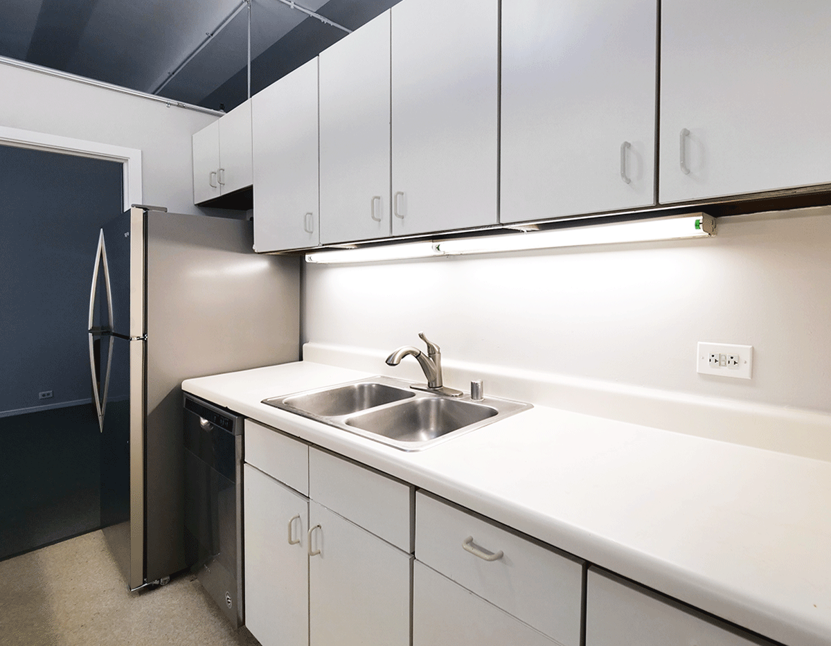 A kitchen with white cabinets and a stainless steel refrigerator