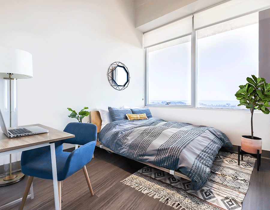 A bedroom with a bed , desk , chair and laptop.