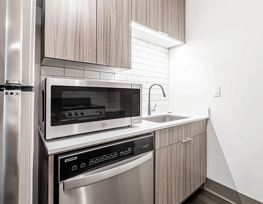 A kitchen with a microwave , dishwasher , refrigerator and sink.