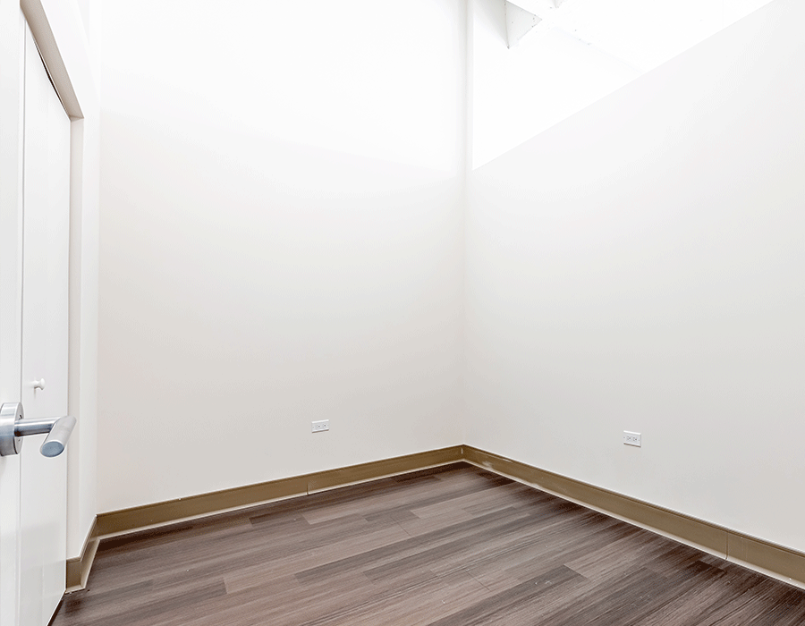 An empty room with a wooden floor and white walls.