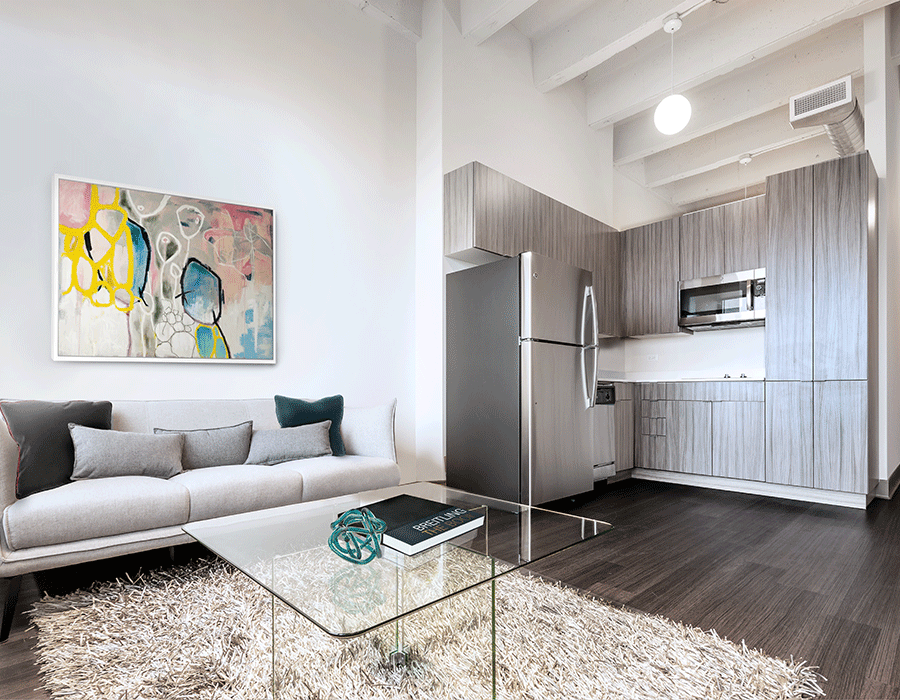 A living room with a couch , coffee table , and kitchen.