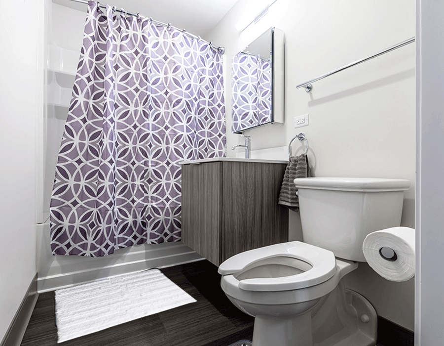 A bathroom with a toilet , sink , shower and purple shower curtain.