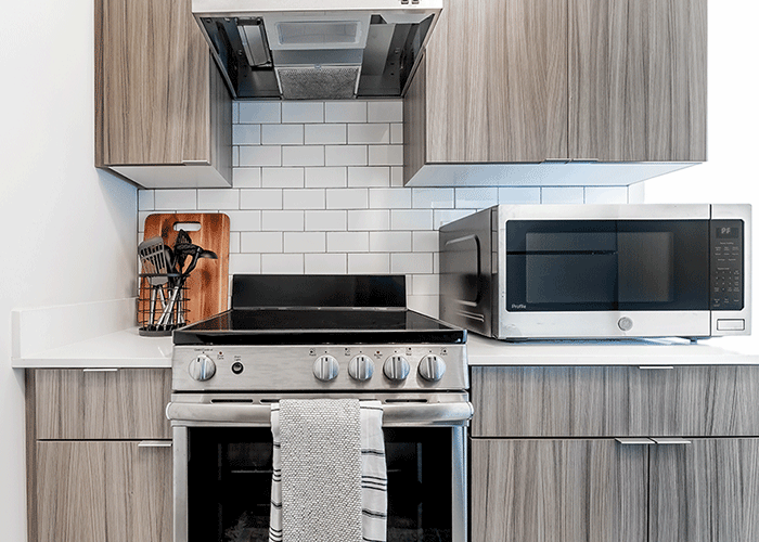A kitchen with a stove , microwave , and cabinets.