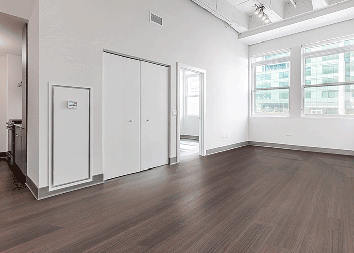 A large empty room with hardwood floors and white walls.