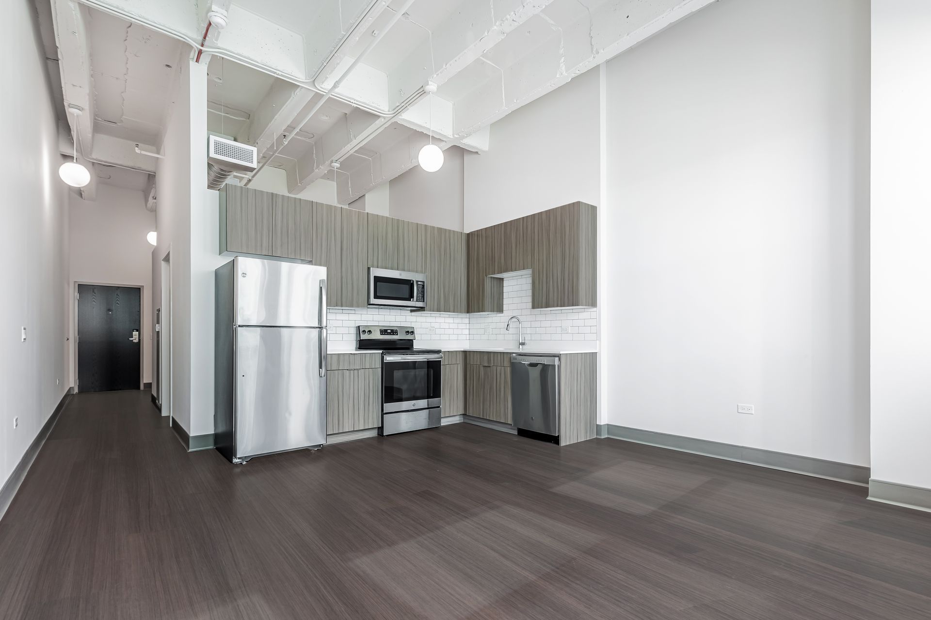 An empty kitchen with stainless steel appliances and wooden cabinets.