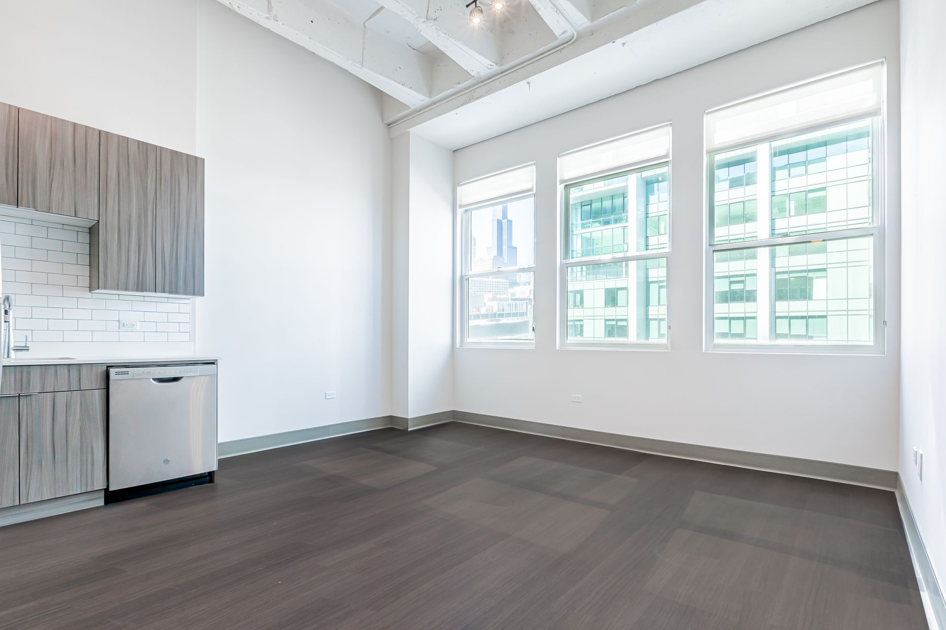 An empty room with a kitchen and a lot of windows.