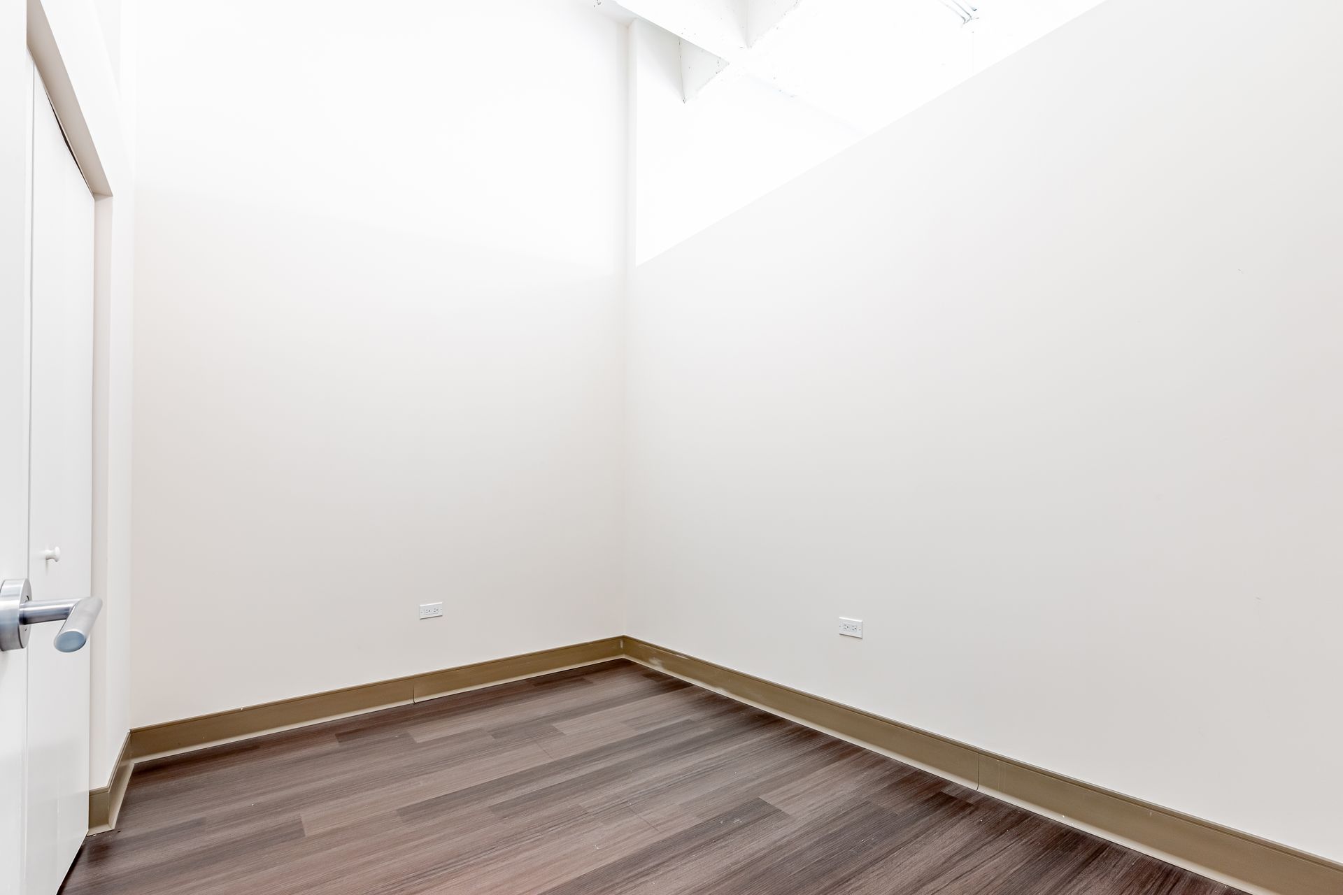 An empty room with hardwood floors and white walls.