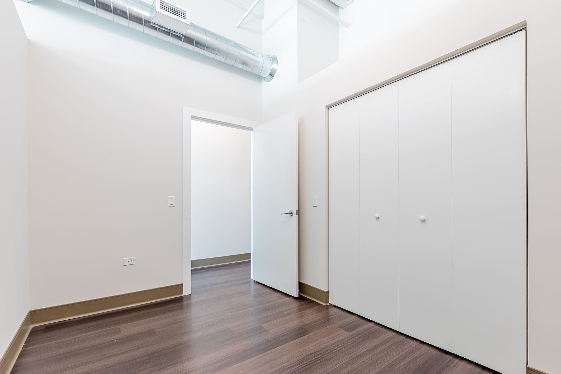 An empty room with hardwood floors and white walls