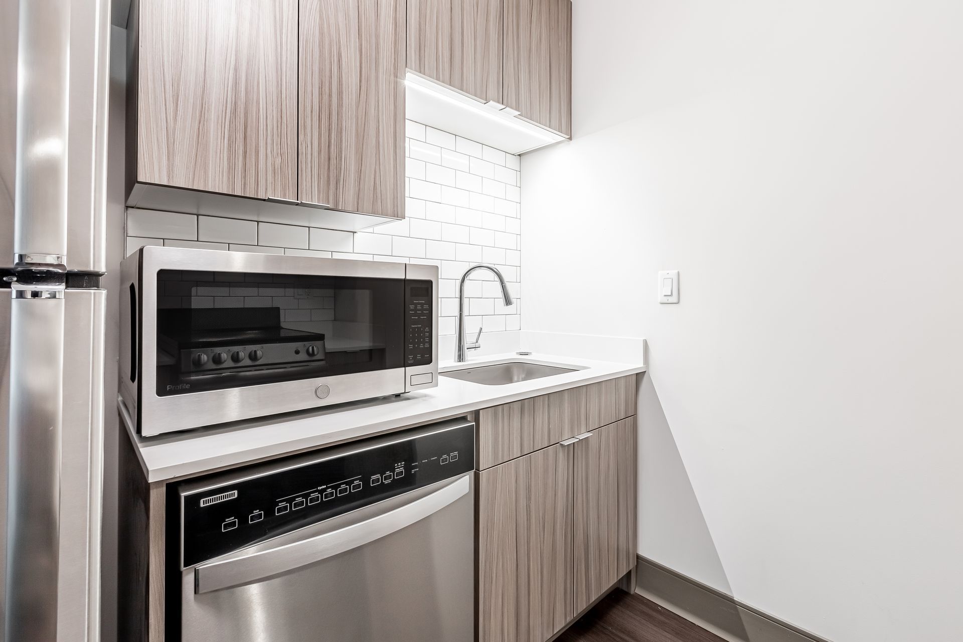 A kitchen with a refrigerator , microwave , dishwasher and sink.