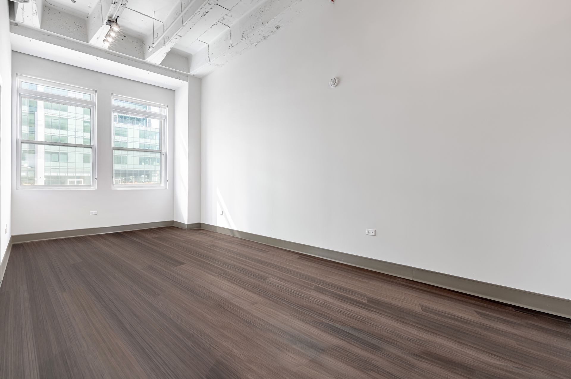 An empty room with hardwood floors and white walls.