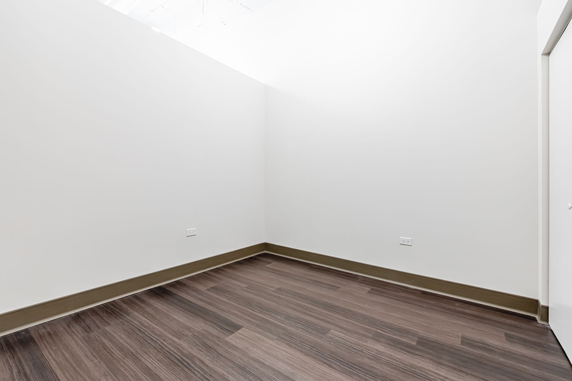 An empty room with a wooden floor and white walls.