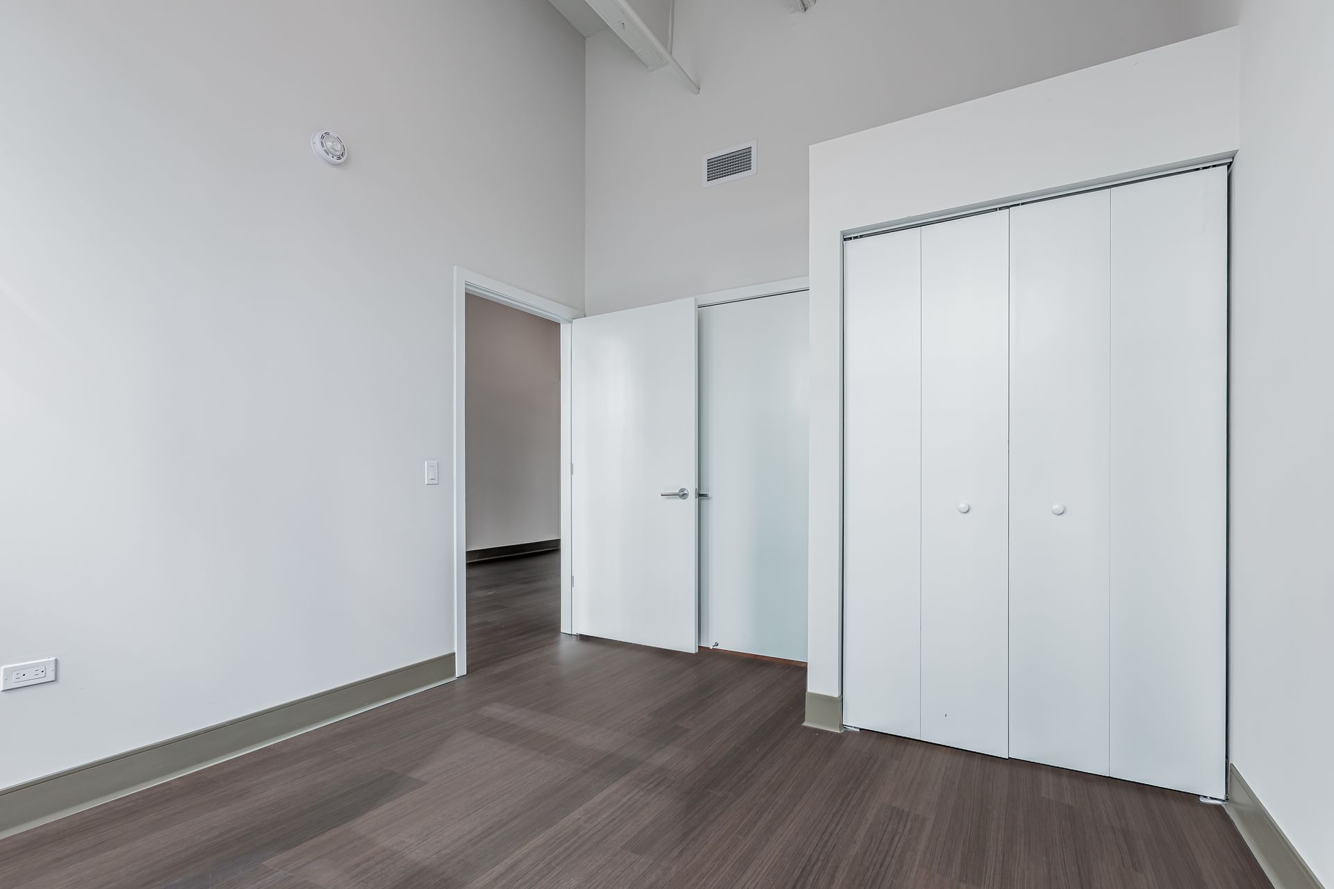 An empty room with hardwood floors and white walls.