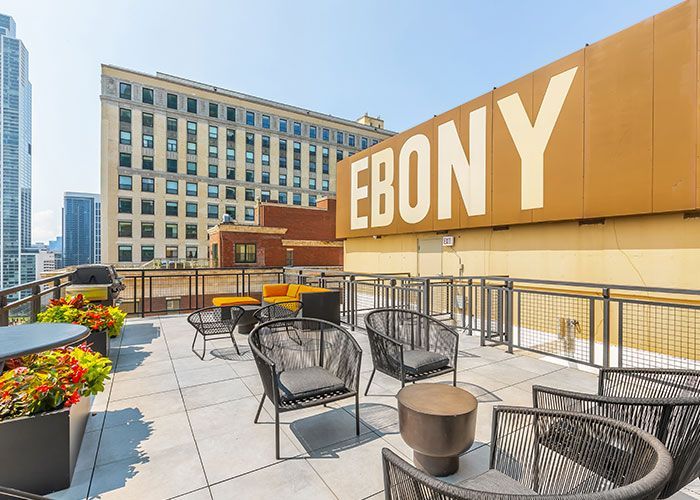 A rooftop patio with chairs , tables and a large sign that says ebony.