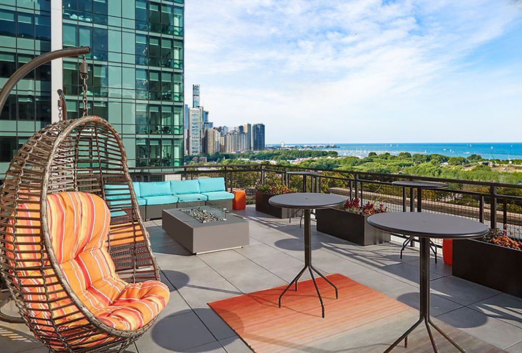 There is a hanging chair and a table on the roof of a building.