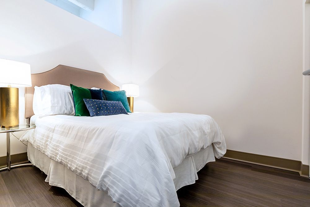 A bedroom with a bed , two lamps , and a window.