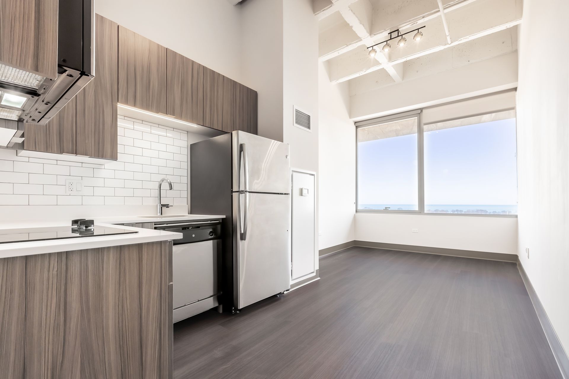 A kitchen with a refrigerator , dishwasher , sink , and large window.