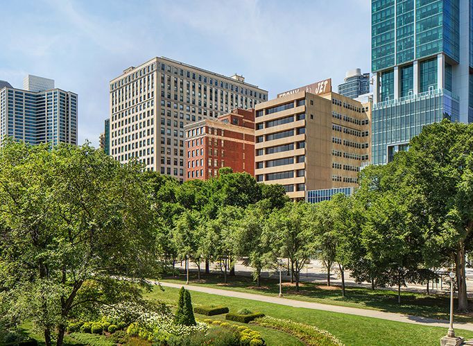 A park in the middle of a city with tall buildings in the background.