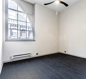 An empty room with a window and a ceiling fan