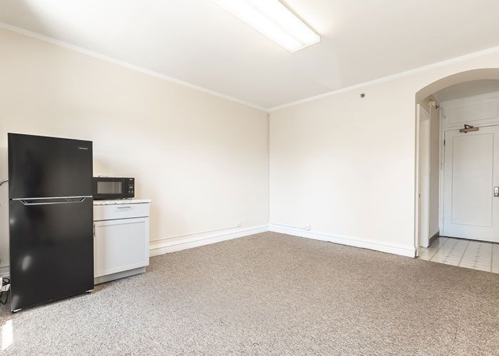 A living room with a black refrigerator , white dishwasher , and microwave.