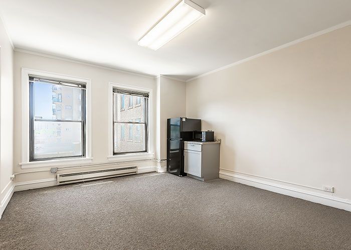 An empty room with a desk and two windows.
