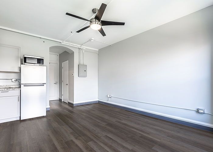 An empty room with a ceiling fan and a refrigerator.