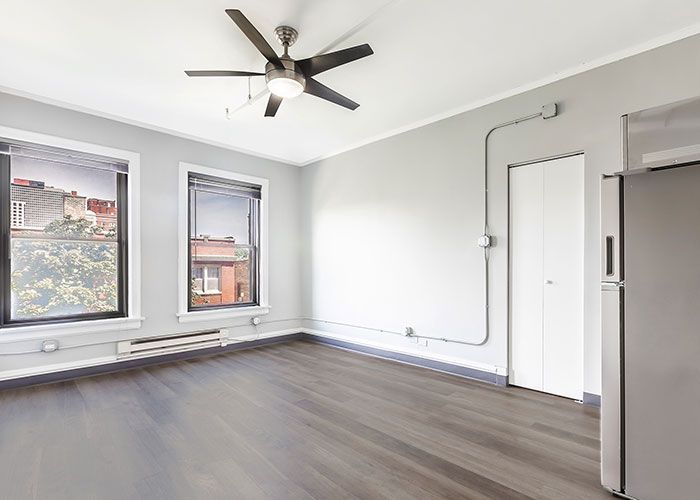 An empty room with a ceiling fan and a refrigerator.
