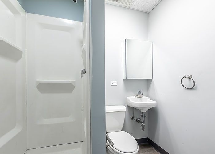 A bathroom with a toilet , sink and shower.