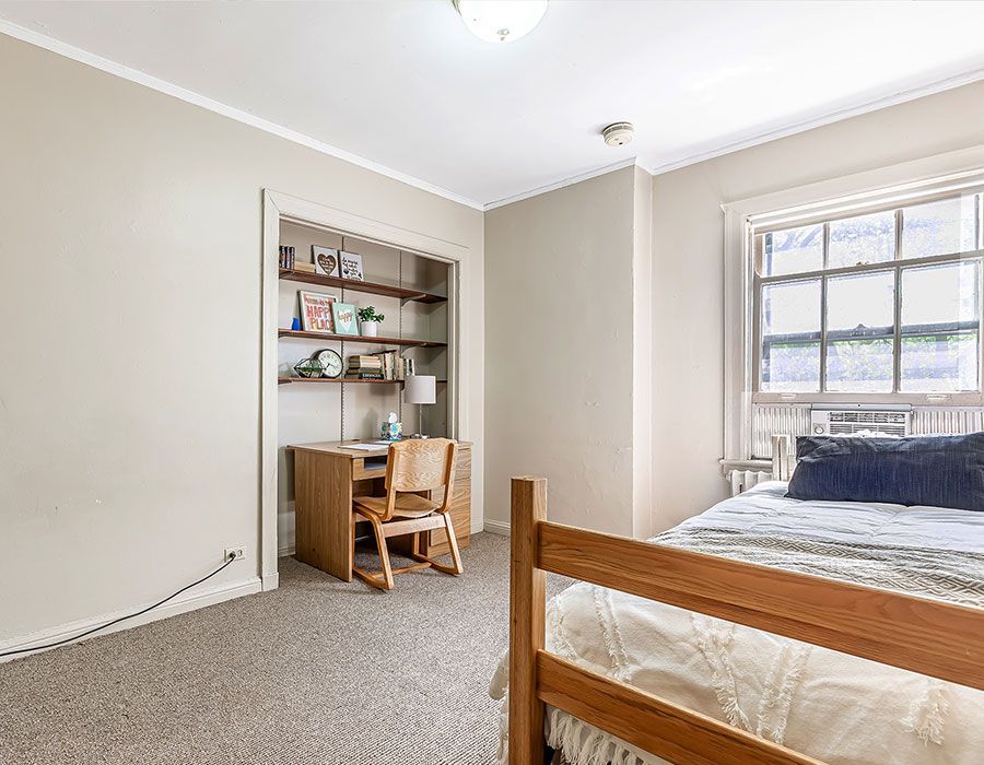 A bedroom with a bed , desk , chair and window.
