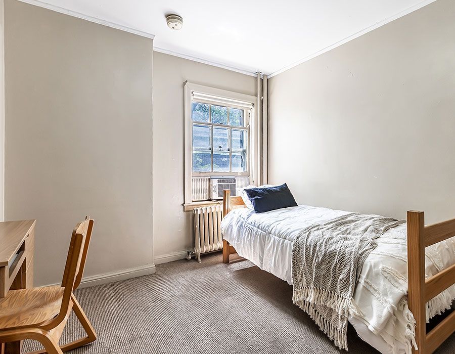 A bedroom with a single bed , desk , chair and window.