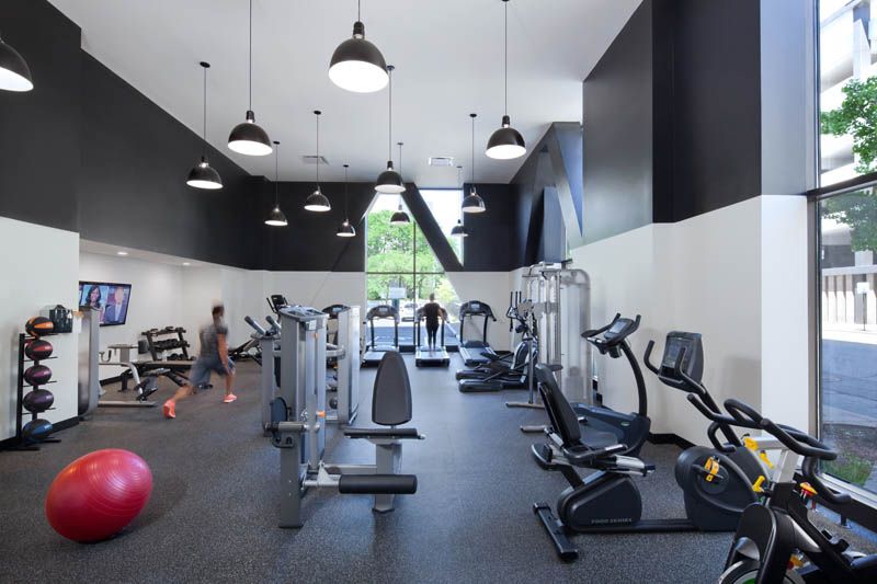 A man is running in a gym with a red ball on the floor