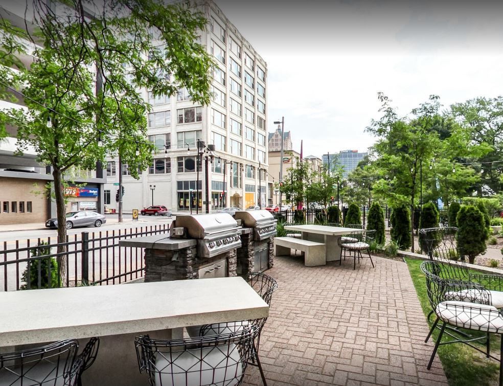 A patio with tables and chairs and a grill in front of a building.